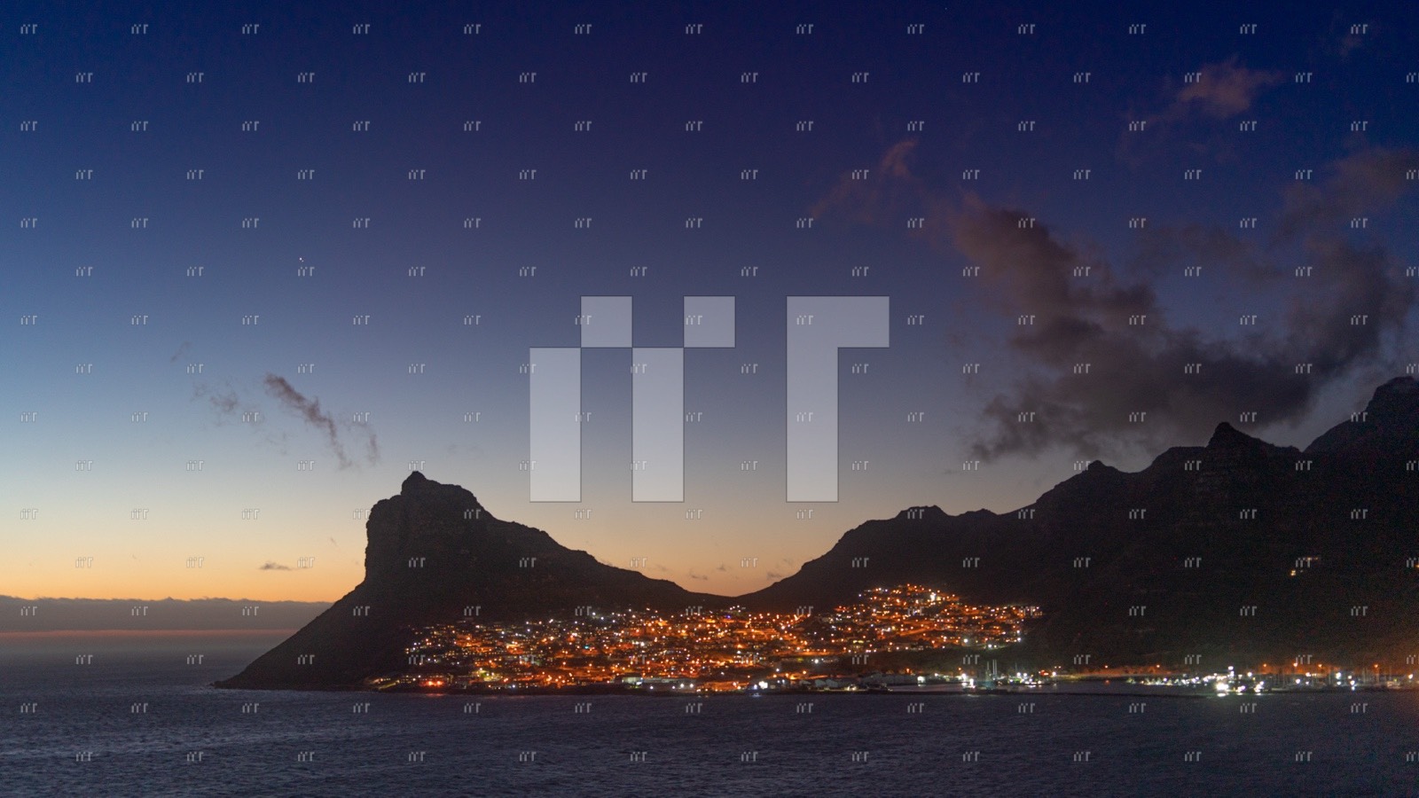 Hout Bay lit up below dark mountains at twilight, with Jupiter bright in the sky