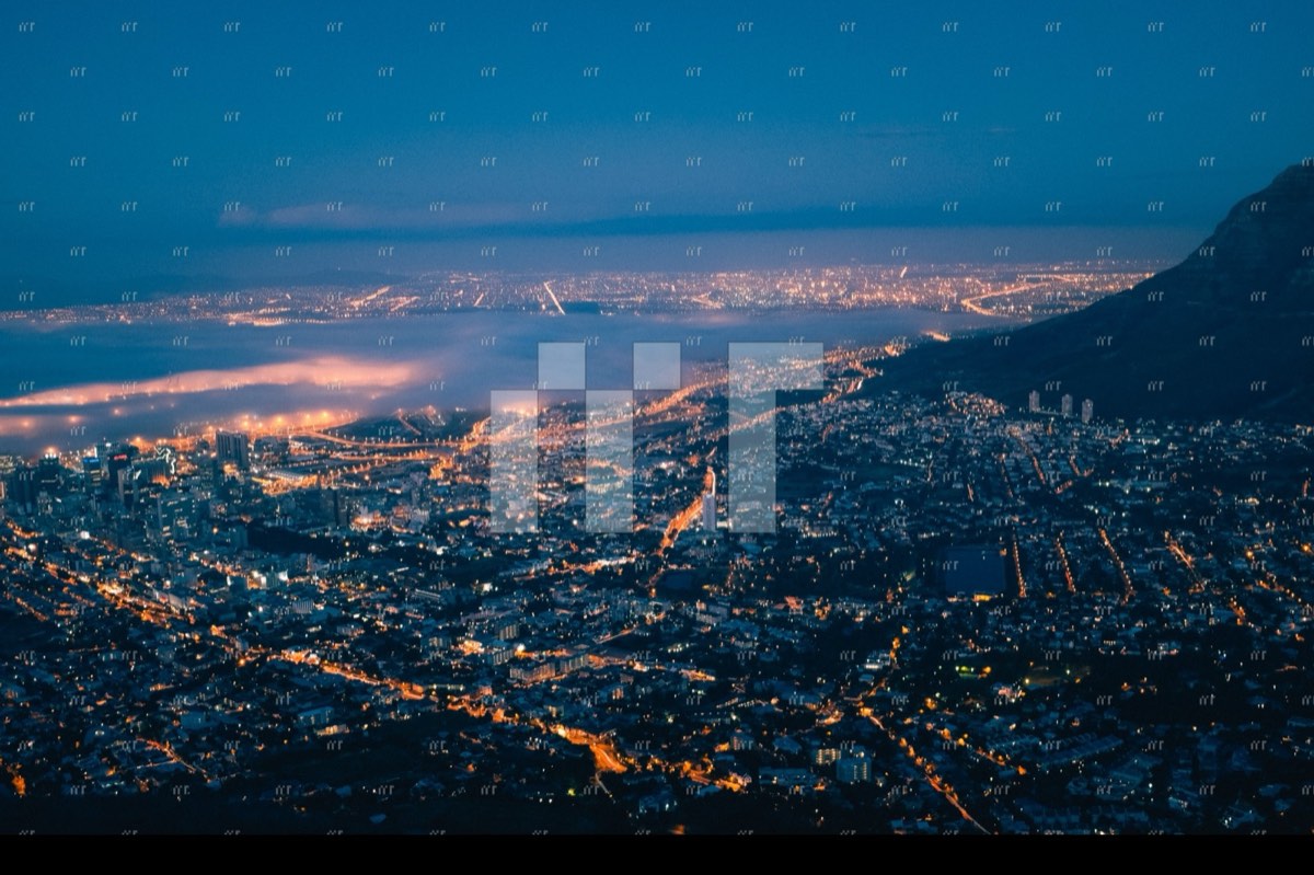 Cape Town's lights spreading around the foot of Table Mountain at night, seen from Lion's Head