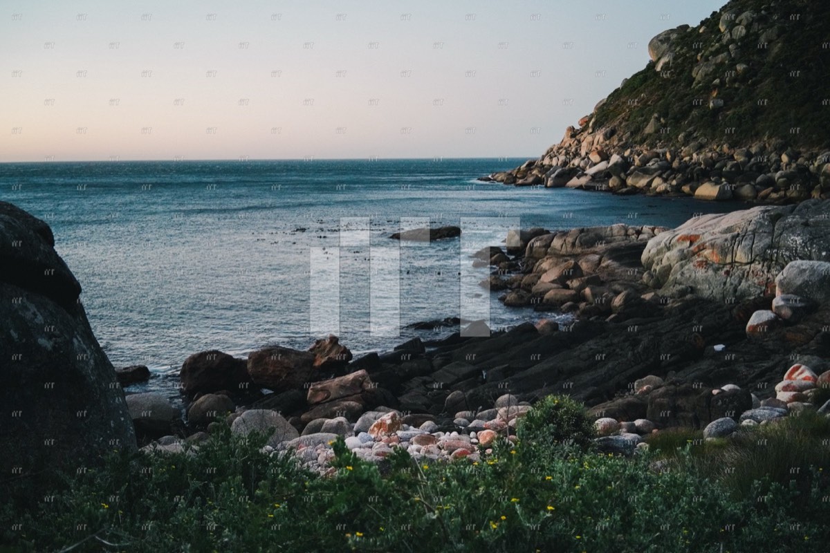 A rocky coastline and calm sea in soft evening light