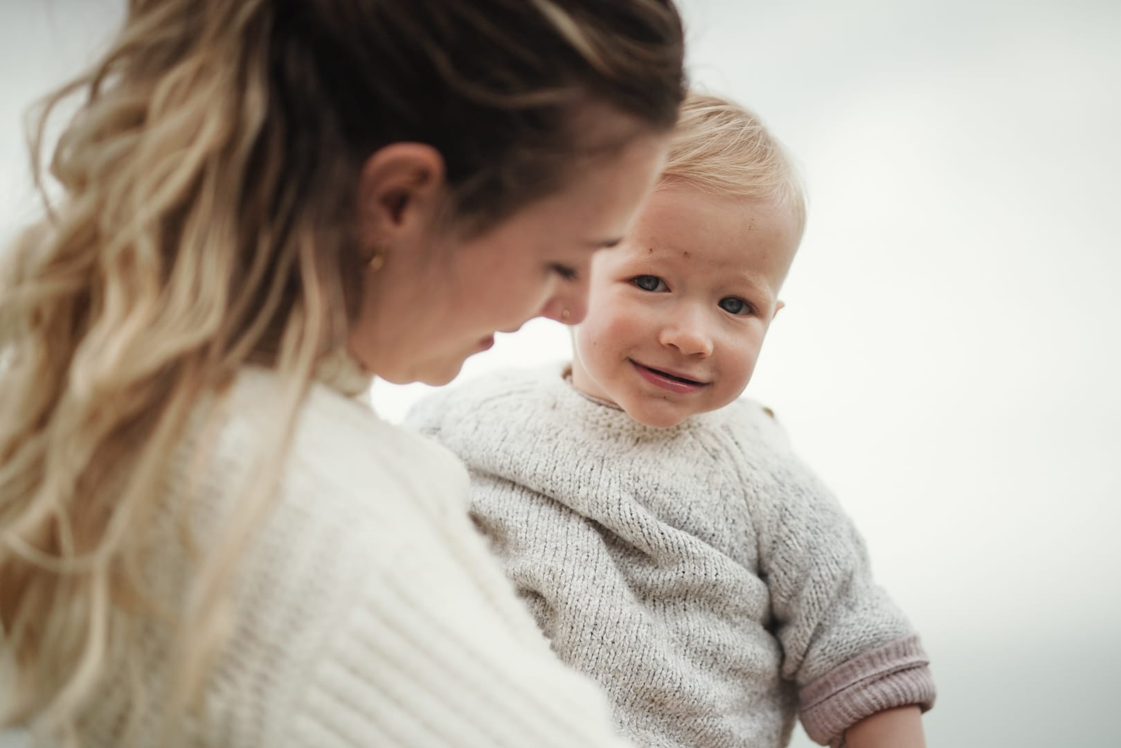 A mother holding her baby outdoors in soft light