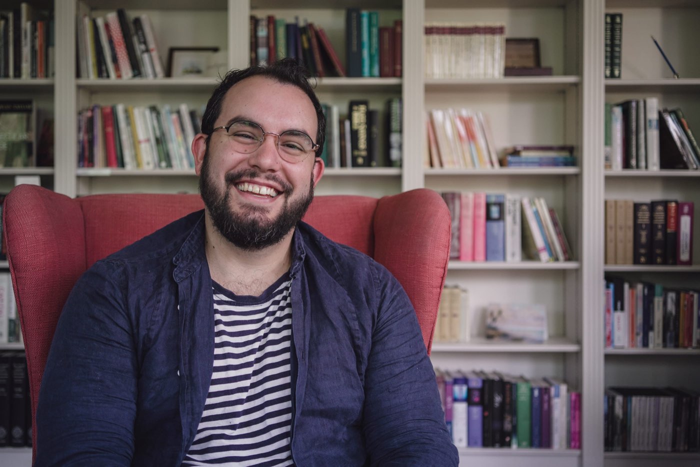 A man laughing in front of a bookshelf