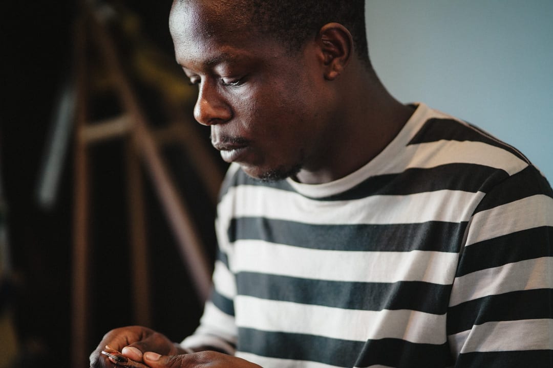 A man in a striped top concentrating on detailed handwork