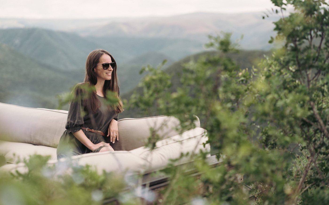 A woman standing on a terrace with mountains behind her